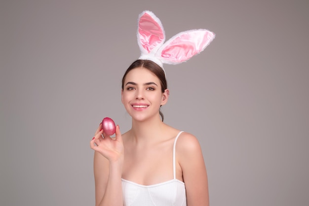 Portrait de jeune femme portant des oreilles de lapin tenant des oeufs de Pâques sur fond isolé en studio