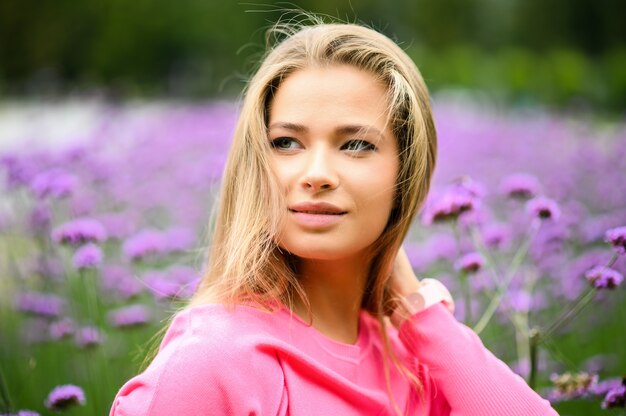 Portrait de jeune femme posant contre des fleurs violettes