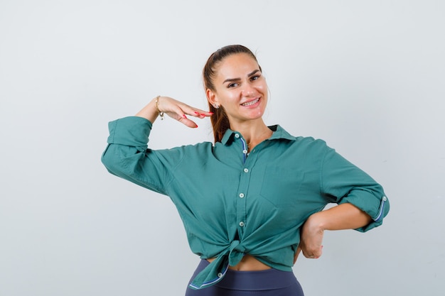 Portrait de jeune femme posant debout en chemise verte et à la vue de face joyeuse