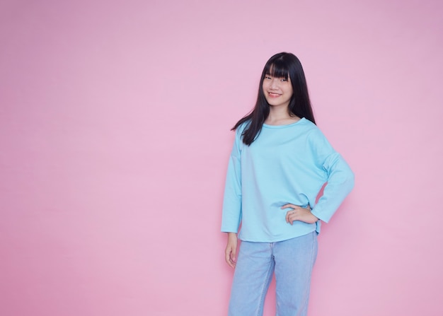 Portrait de jeune femme posant sur un mur rose