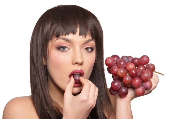 Portrait de jeune femme posant avec des raisins sur fond blanc