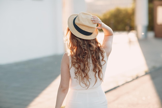 Portrait de jeune femme positive aux cheveux bouclés en chapeau de paille
