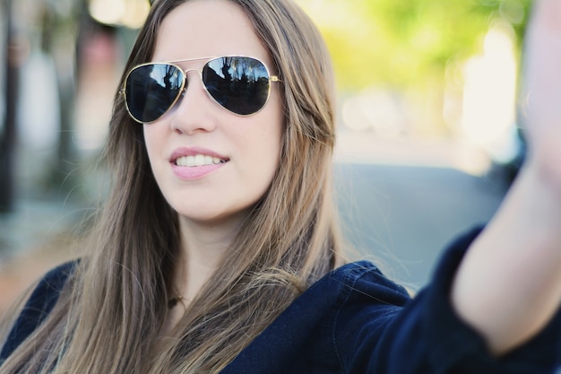 Portrait de jeune femme prenant selfie.