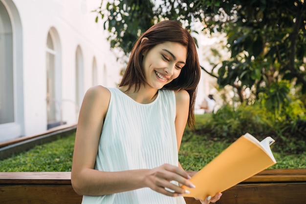 Portrait de jeune femme profitant de son temps libre et lisant un livre assis à l'extérieur. Concept de mode de vie.