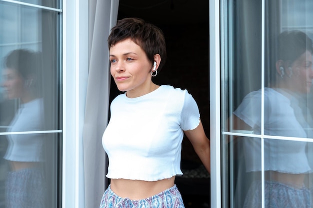 Portrait d'une jeune femme qui se retrouve le matin sur son balcon dans un appartement