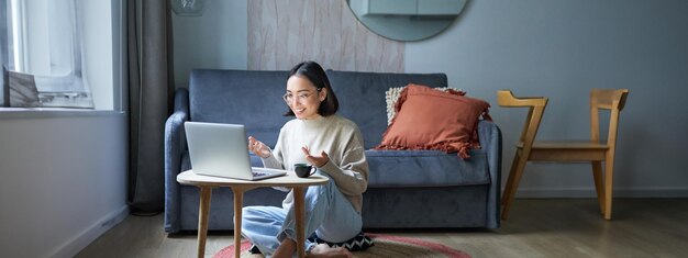 Portrait d'une jeune femme qui travaille, une fille coréenne qui étudie à distance en ligne et qui parle à un chat vidéo sur un ordinateur portable