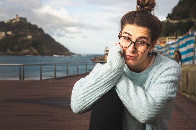 Photo portrait d'une jeune femme de race blanche assise sur un banc à la mer