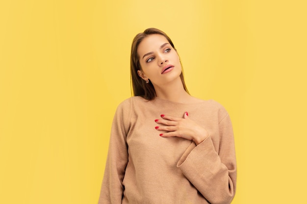 Portrait de jeune femme de race blanche avec des émotions vives isolées sur fond de studio jaune