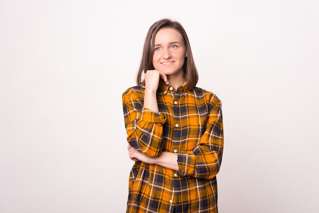 Portrait d'une jeune femme réfléchie et rêveuse sur fond blanc.