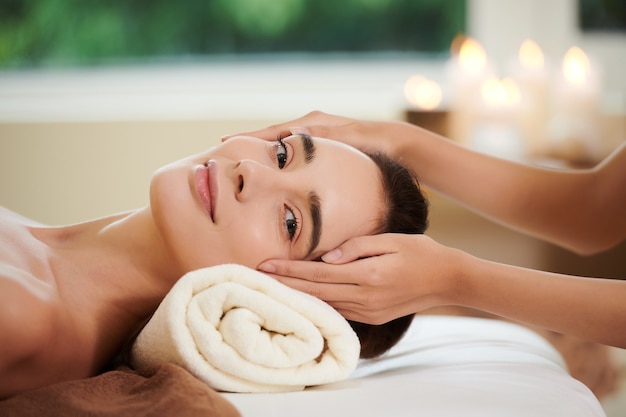 Portrait de jeune femme regardant la caméra tout en se faisant masser