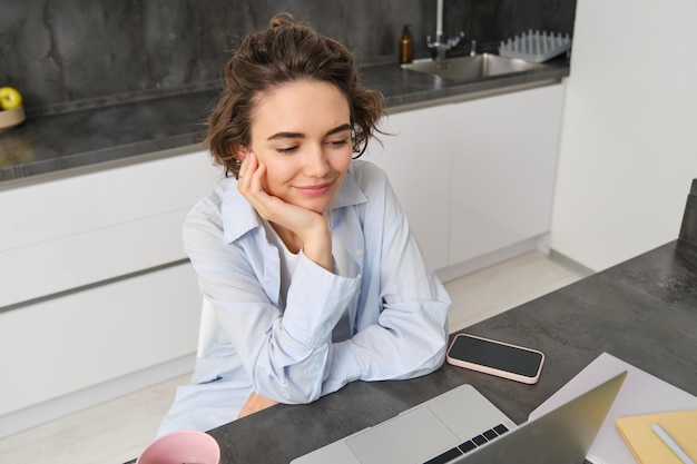 Portrait d'une jeune femme regardant une vidéo sur un ordinateur portable travaillant à domicile et étudiant en ligne