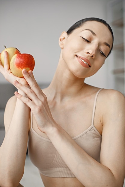 Portrait de jeune femme de remise en forme à la maison tenant des pommes fraîches