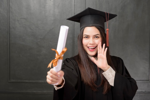 Portrait de jeune femme en robe de graduation souriant et acclamant