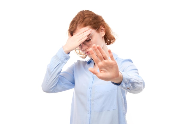 Portrait de jeune femme rousse montrant un panneau d'arrêt avec la main isolé sur fond blanc