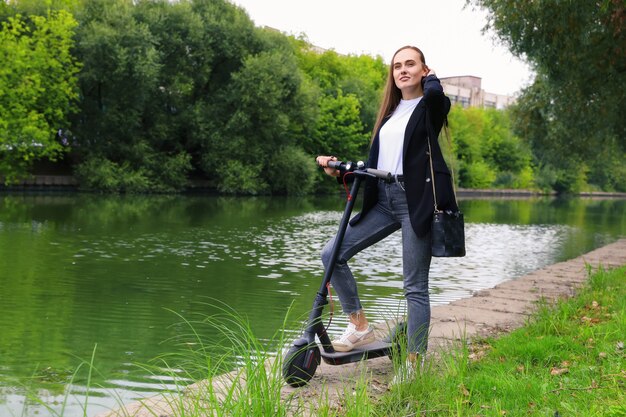 Portrait d'une jeune femme avec un scooter électrique dans le parc