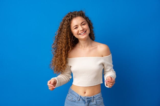 Portrait d'une jeune femme séduisante aux cheveux bouclés sur fond bleu