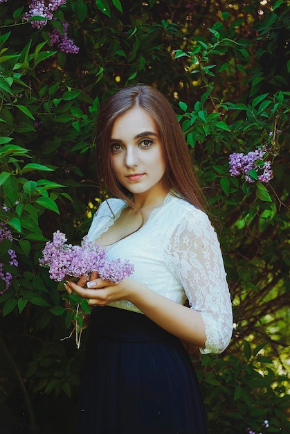 Portrait de jeune femme séduisante dans le jardin de printemps avec un bouquet de lilas. Fond de printemps.