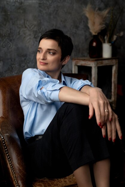 Portrait de jeune femme séduisante dans des vêtements décontractés assis dans un fauteuil à l'ancienne