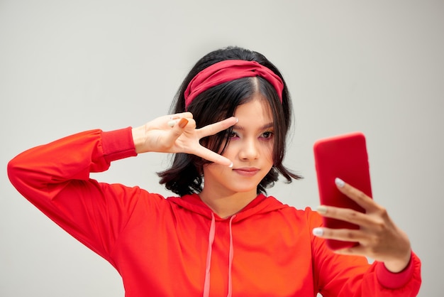 Portrait d'une jeune femme séduisante faisant selfie photo sur smartphone isolé sur fond blanc