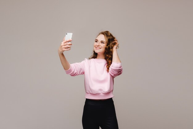 Portrait d'une jeune femme séduisante faisant selfie photo sur smartphone isolé
