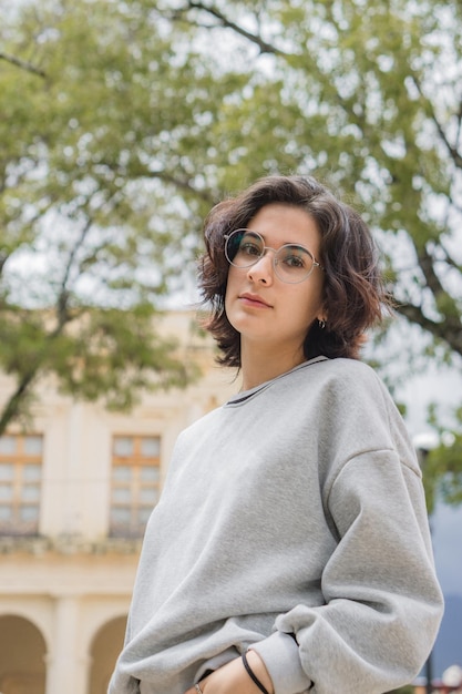 Portrait d'une jeune femme seule regardant la caméra, dans un parc.