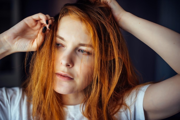 Portrait de jeune femme sexy touchant de longs cheveux roux. Modèle féminin posant en studio, gros plan du visage.
