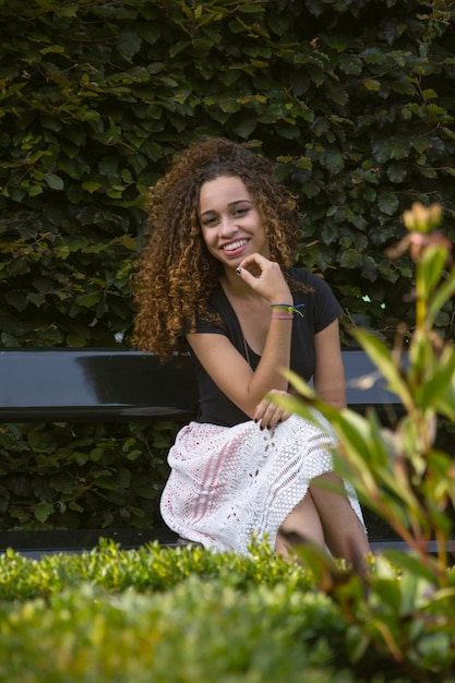 Portrait d'une jeune femme souriante assise sur un banc