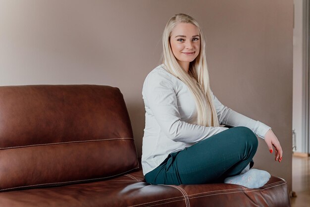 Photo portrait d'une jeune femme souriante assise sur le canapé à la maison