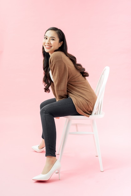 Portrait d'une jeune femme souriante assise sur une chaise