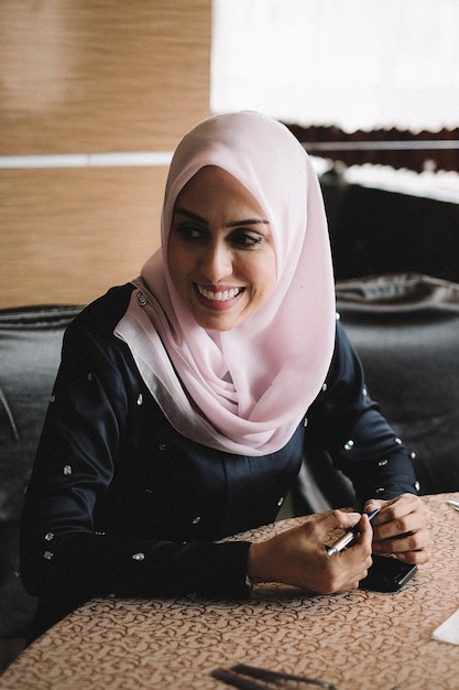 Photo portrait d'une jeune femme souriante assise à l'intérieur