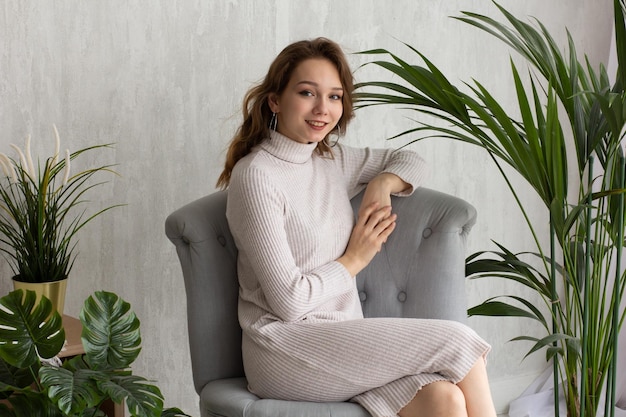 Portrait de jeune femme souriante assise regardant la caméra sur le fond du mur blanc