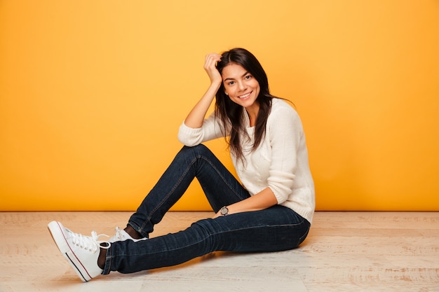 Portrait d'une jeune femme souriante assise sur un sol