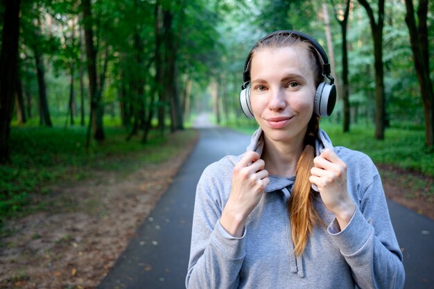 Portrait de jeune femme souriante au repos après avoir fait du jogging et écouter de la musique. Mode de vie sportif sain. Fitness et entraînement en plein air.