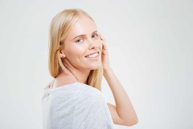 Portrait d'une jeune femme souriante avec un beau visage regardant à l'avant isolé sur un mur blanc