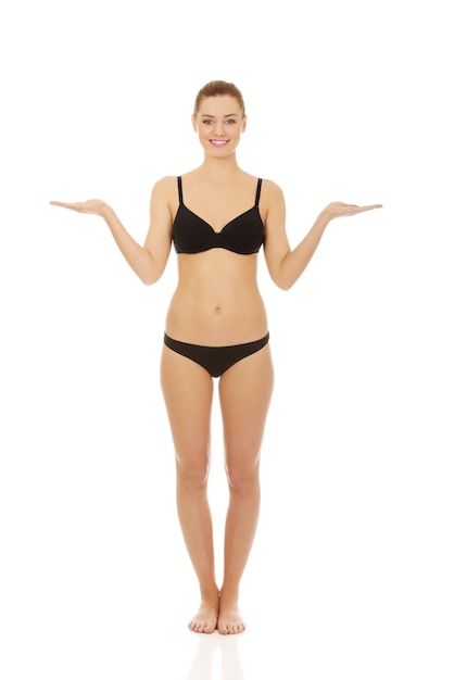 Portrait d'une jeune femme souriante en bikini debout sur un fond blanc