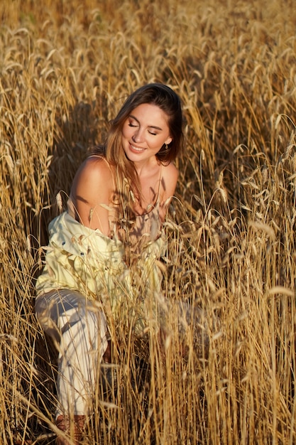 Portrait d'une jeune femme souriante blonde sur fond de champ de blé doré