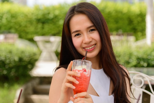 Portrait d'une jeune femme souriante buvant une boisson