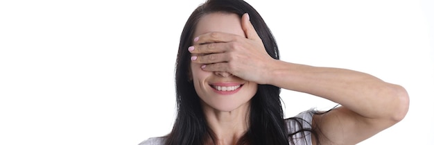 Portrait de jeune femme souriante couvrant ses yeux avec le concept d'émotions féminines à la main