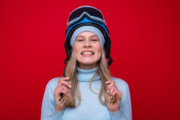 Portrait d'une jeune femme souriante dans un chandail, un casque et des lunettes de ski