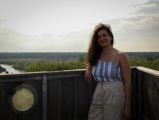 Portrait d'une jeune femme souriante debout contre la balustrade