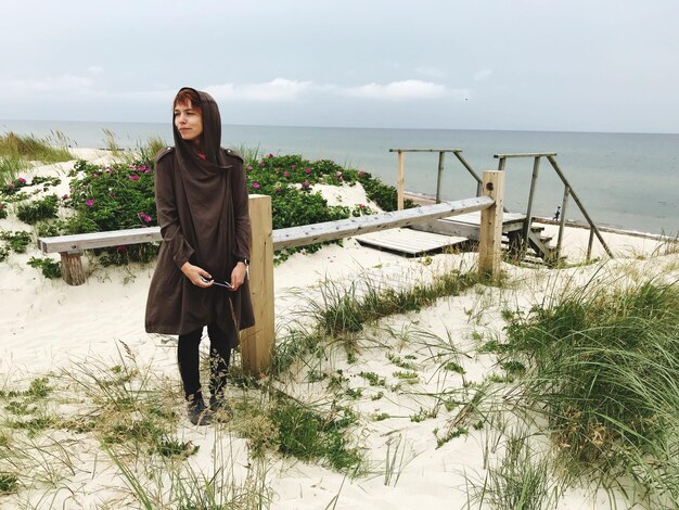 Portrait d'une jeune femme souriante debout contre la mer