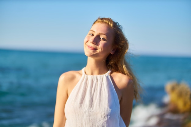 Portrait d'une jeune femme souriante debout sur la plage