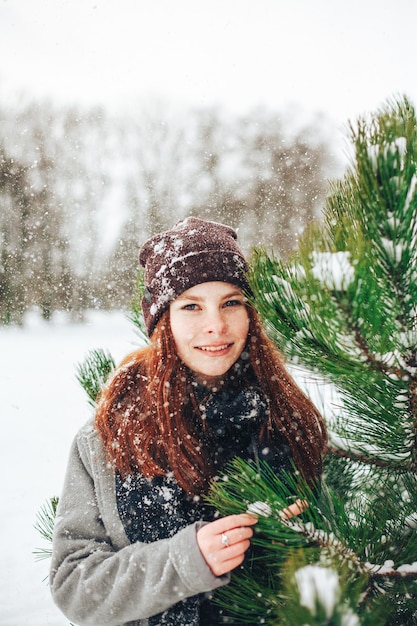 Portrait d'une jeune femme souriante debout près d'un arbre en hiver