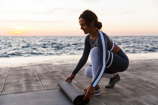 Portrait, de, a, jeune femme souriante, dérouler tapis fitness