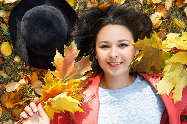 Portrait de jeune femme souriante avec des feuilles d'automne