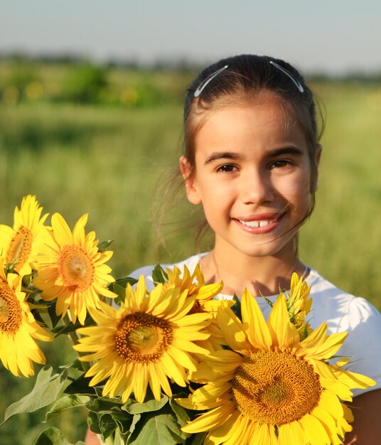Photo portrait d'une jeune femme souriante avec une fleur jaune sur le champ