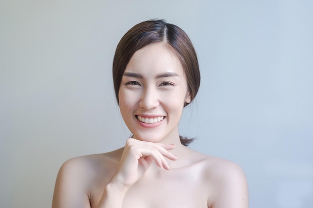 Portrait d'une jeune femme souriante sur un fond gris