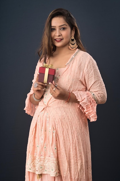 Portrait d'une jeune femme souriante heureuse fille tenant une boîte-cadeau sur un fond gris