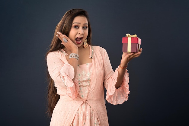 Portrait d'une jeune femme souriante heureuse fille tenant une boîte-cadeau sur un fond gris