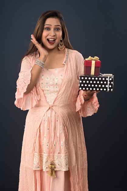 Portrait d'une jeune femme souriante heureuse fille tenant une boîte-cadeau sur un fond gris